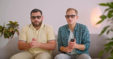 Tv'de korku filmi izleyen iki beyaz komik adamın kapalı mekanda kanepede otururken ki yakın çekim portresi