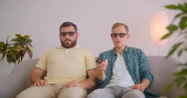 Tv'de korku filmi izleyen iki beyaz komik adamın yakın çekim portresi birlikte kanepede oturarak içeride zıplamak