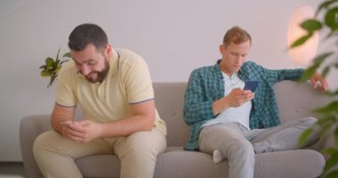 İki beyaz adamın, arka koltukta birlikte oturduğu telefonlarını kullanan iki beyaz adamın kapalı mekanda samimi bir şekilde portreleri. Komik mesajlar paylaşan arkadaşlar gülüyor