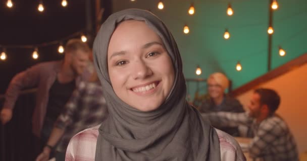 Zbliżenie Portret młodej całkiem muzułmańskiej kobiety w hidżab na zróżnicowanej imprezie w przytulnym wieczorem — Wideo stockowe