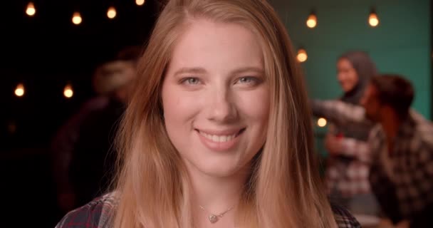 Zbliżenie Portret młodej całkiem blond długowłosy kobieta patrząc na aparat uśmiechnięty szczęśliwie na zróżnicowanej imprezie w przytulnym wieczorem — Wideo stockowe