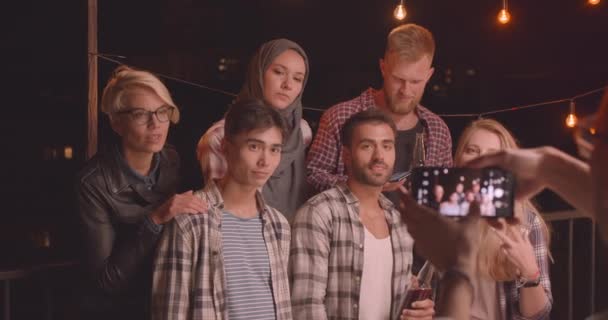 Zbliżenie portret zróżnicowanej grupy wielorasowe przyjaciół jest fotografowany na telefon na imprezę zabawy w przytulnym wieczorem — Wideo stockowe
