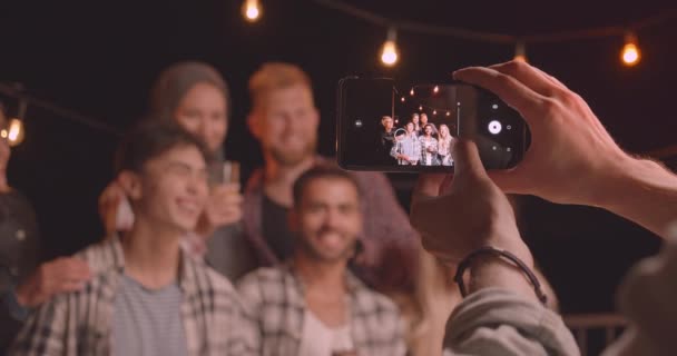 Zbliżenie portret zróżnicowanej grupy wielorasowe przyjaciół jest fotografowany na Instagramie kamery na imprezie zabawy w przytulnym wieczorem z lampkami wróżek — Wideo stockowe