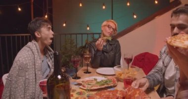 Peri ışıkları ile rahat bir akşam serin partide mutlu bir şekilde kutlayan pizza yiyen arkadaş çeşitli çok ırklı grup Closeup portre