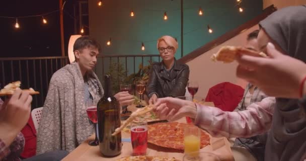 Closeup portrait of diverse multiracial group of friends eating pizza celebrating happily at cool party in cozy evening — Stock Video