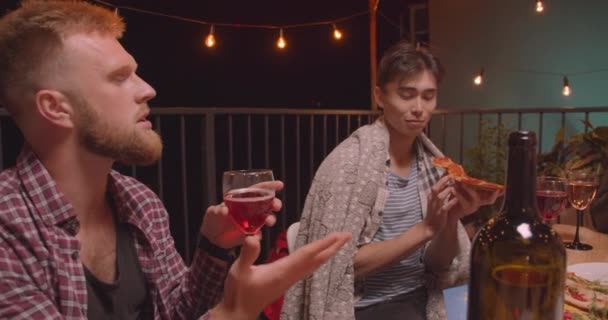 Primo piano ritratto di diversi gruppi di amici che mangiano pizza festeggiando alla festa fresca in serata accogliente con luci fatate sullo sfondo — Video Stock
