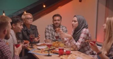 Arka planda peri ışıkları ile rahat bir akşam serin partide pizza yeme ve şarap içme arkadaş çeşitli çok ırklı grup Closeup portre