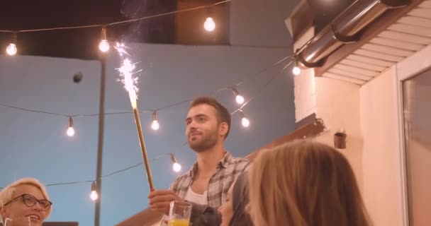 Closeup portrait of diverse multiracial group of friends eating pizza and drinking wine with firework stick at party in cozy evening — Stock Video
