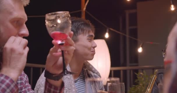 Portrait rapproché de l'homme asiatique mangeant de la pizza dans divers groupes multiraciaux d'amis dans une soirée confortable avec des lumières de fées sur fond — Video