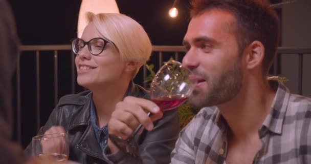 Closeup portrait of caucasian woman and man in diverse multiracial group of friends in cozy evening with fairy lights on background — Stock Video