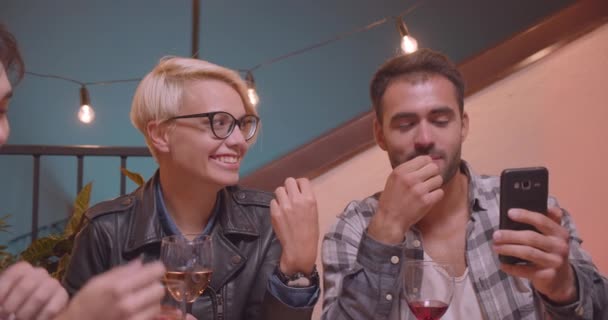 Closeup portrait of diverse multiracial group of friends eating chinese bugs and taking pictures in evening with fairy lights on background — Stock Video