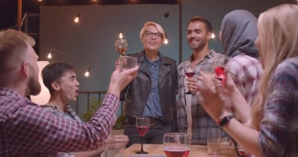 Primer plano retrato de feliz pareja haciendo un anuncio sobre el matrimonio en diversos grupos multirraciales de amigos bebiendo vino en la fiesta — Vídeos de Stock