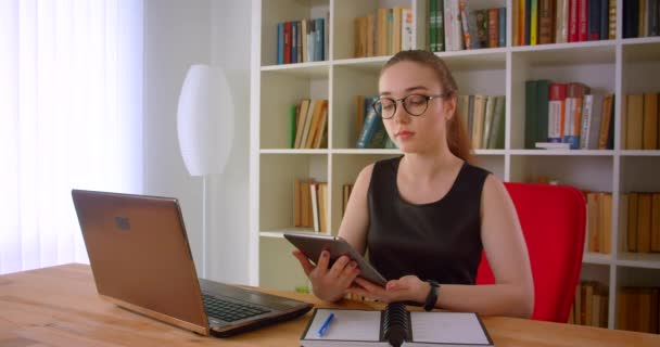 Closeup portré fiatal csinos vöröshajú üzletasszony a szemüveg segítségével tabletta bemutató zöld képernyő kamera előtt ülve laptop hivatalban — Stock videók
