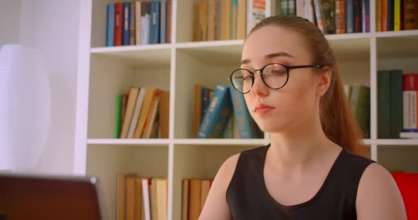 Closeup portrét mladé, červenaté ženy v brýlích za použití laptopu ve vnitřní místnosti — Stock video