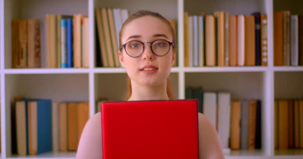 特写镜头中年轻的成功红发女，戴着眼镜，在室内办公室开心地微笑着 — 图库视频影像