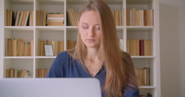 Retrato de close-up de jovem atraente mulher de negócios caucasiana usando laptop olhando para a câmera no escritório dentro de casa — Vídeo de Stock