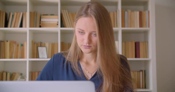 Retrato de close-up de jovem atraente mulher de negócios caucasiana usando laptop olhando para a câmera sorrindo alegremente no escritório dentro de casa — Vídeo de Stock