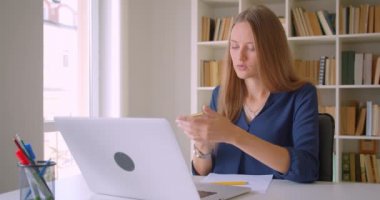 Genç çekici beyaz iş kadını dizüstü bilgisayar kullanarak closeup portre ofis kapalı notlar alarak telefon görüşmesi yapıyor
