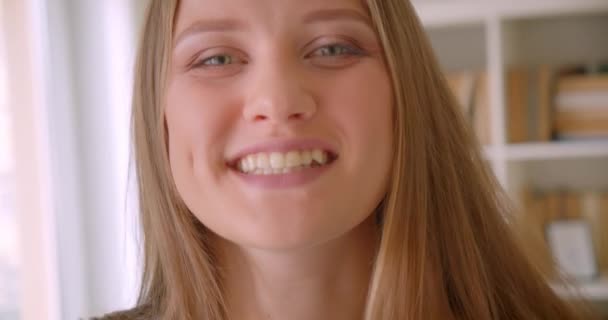 Κοντινό πλάνο του νεαρού ελκυστικό καυκάσιο κορίτσι κοιτάζοντας την κάμερα γελώντας ευτυχισμένα στο διαμέρισμα σε εσωτερικούς χώρους — Αρχείο Βίντεο