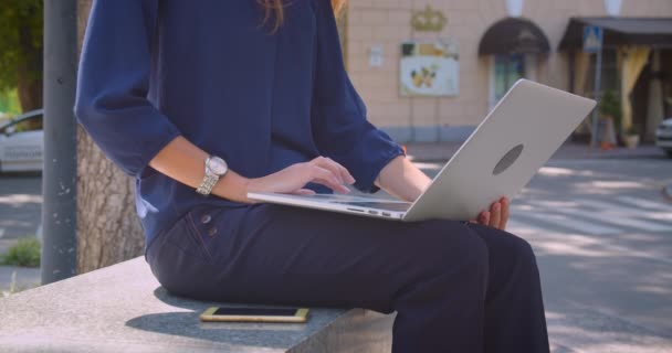 Крупним планом портрет молодої досить кавказької бізнес-леді, що друкує на ноутбуці в парку на відкритому повітрі в місті — стокове відео
