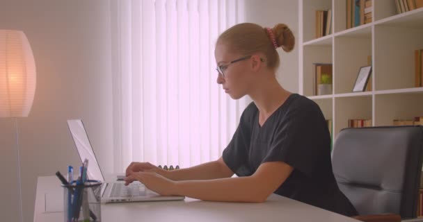 Крупним планом портрет молодої привабливої бікіні в окулярах, використовуючи ноутбук в офісі в приміщенні — стокове відео