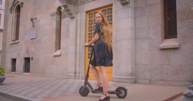 Sokakta kamera açık havada bakarak kick scooter tutan gözlük uzun saçlı genç çekici kafkas kadın Closeup portre