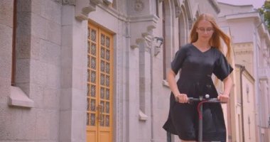 Gözlük ve elbise sürme kick scooter açık uzun saçlı genç güzel beyaz kadın Closeup portre