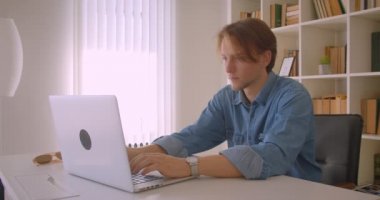 Ofis kapalı dizüstü bilgisayar kullanarak genç çekici kafkas işadamı closeup portre