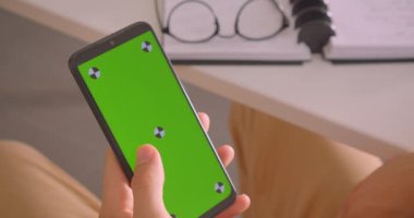 Kapalı yeşil ekranlı bir telefon tutan erkek elin Closeup geri görünüm portresi