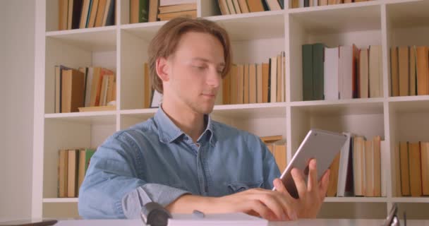 Крупный план портрета молодого привлекательного кавказского бизнесмена, использующего планшет и показывающего зеленый экран на камеру в офисе в помещении — стоковое видео