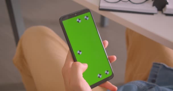 Close-up achteraanzicht portret van mannelijke houden een telefoon met groen scherm binnenshuis — Stockvideo