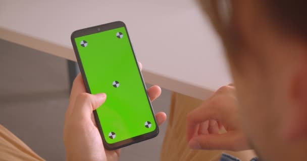 Close-up achteraanzicht portret van mannelijke texting op telefoon met groen Chroma scherm binnenshuis — Stockvideo