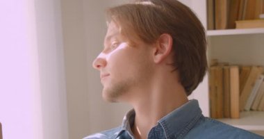 Kütüphanenin penceresinden pencereden bakarak genç yakışıklı beyaz erkek Closeup portre kapalı