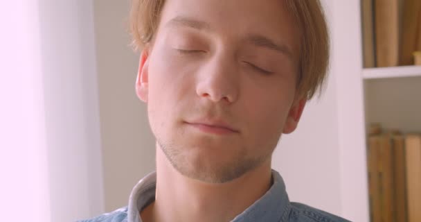 Close-up retrato de jovem bonito caucasiano homem olhando para câmera na biblioteca dentro de casa — Vídeo de Stock