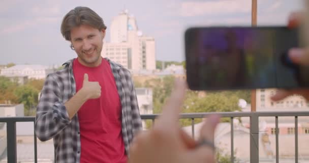 Closeup portréja felnőtt csinos kaukázusi ember, hogy fényképezett telefonon a barátnője állva erkély a ház — Stock videók