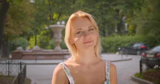 Close-up retrato de adulto loira caucasiano mulher sorrindo feliz olhando para a câmera de pé no parque ao ar livre — Vídeo de Stock