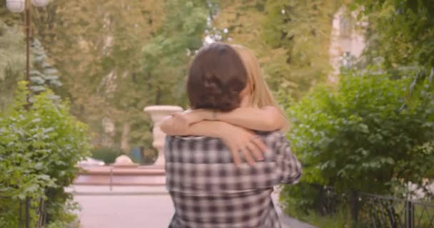 Closeup portrait of adult happy attractive caucasian couple hugging and turning around in park outdoors — Stock Video