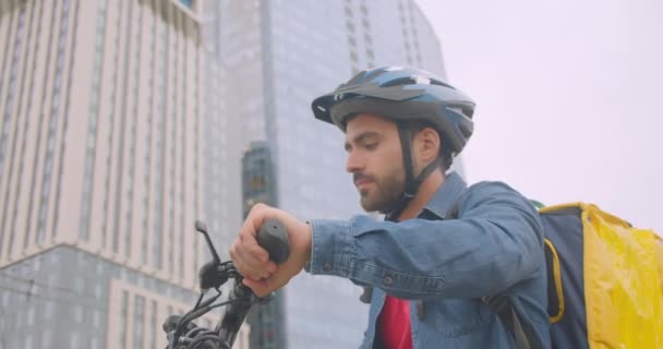 Closeup portréja felnőtt vonzó kaukázusi szállítási ember áll kick robogó és vissza csomag segítségével navigáció app telefonon a városban a szabadban — Stock videók