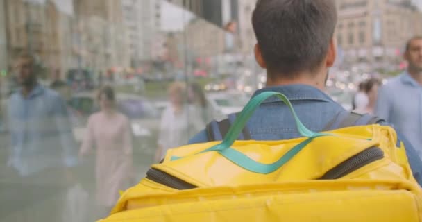 Nahaufnahme Rückseite Porträt eines erwachsenen bärtigen kaukasischen Zusteller mit Rucksack zu Fuß auf der Straße in der Stadt im Freien — Stockvideo