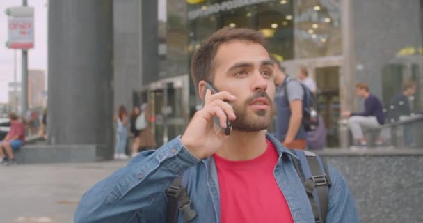 Closeup portrét dospělého muže, který má batoh s batohu, telefonovat na ulici ve městě venku — Stock video