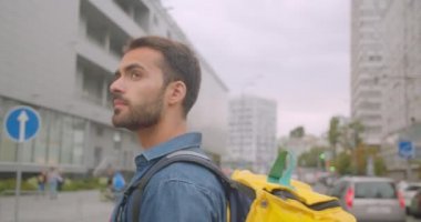 Şehir kazıyıcıları ile şehir açık havada sokakta yürüyen sırt çantası ile sakallı kafkas teslimatçı closeup yan görünüm portresi