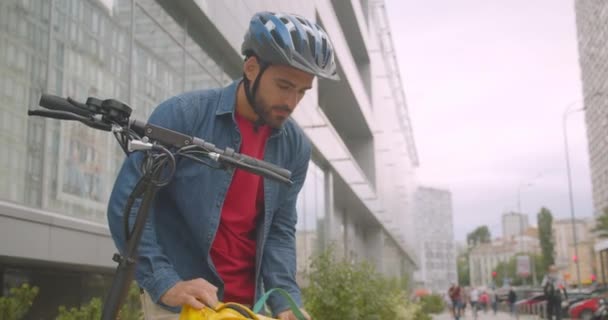 Closeup portrait of bearded caucasian delivery man delivering customer his order in city outdoors with cityscrapers — Stock Video