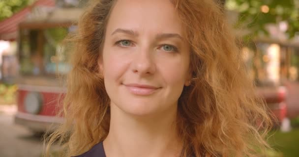 Primer plano retrato de adulto atractivo pelirroja hembra mirando a la cámara sonriendo felizmente en el parque al aire libre — Vídeos de Stock