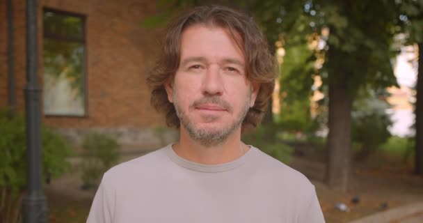 Primer plano retrato de atractivo hombre caucásico mirando a la cámara en la ciudad al aire libre — Vídeos de Stock