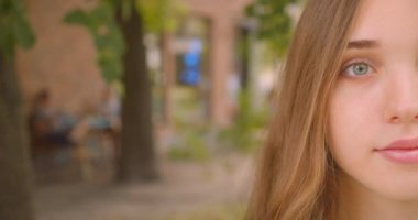 Closeup yarım genç sevimli kafkas kadın portre kamera neşeyle park açık havada ayakta gülümseyerek bakıyor