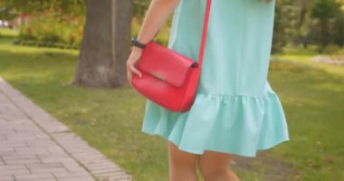 Park açık havada rüzgarda gurur elbisesi ile çanta yürüyüş ile genç güzel kadın Closeup geri görünümü portresi