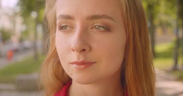 Closeup retrato de jovem mulher branca bonito com cabelo loiro olhando para a câmera em pé no parque ao ar livre — Vídeo de Stock