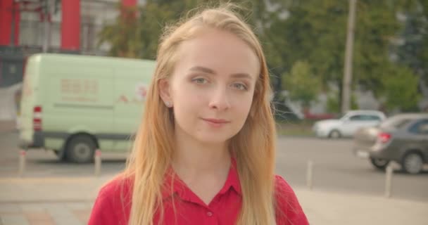 Closeup retrato de jovem bela mulher caucasiana em vestido vermelho olhando para a câmera sorrindo alegremente em pé na cidade urbana ao ar livre — Vídeo de Stock