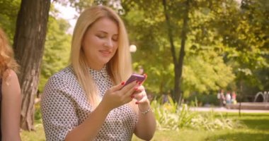 İki güzel kadın arkadaş komik mesajlar paylaşan telefon kullanarak Closeup portre mutlu park açık havada battaniye üzerinde oturan gülüyor