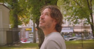 Park açık havada duran mutlu beyaz adam etrafında hareket kamera ile Closeup portre